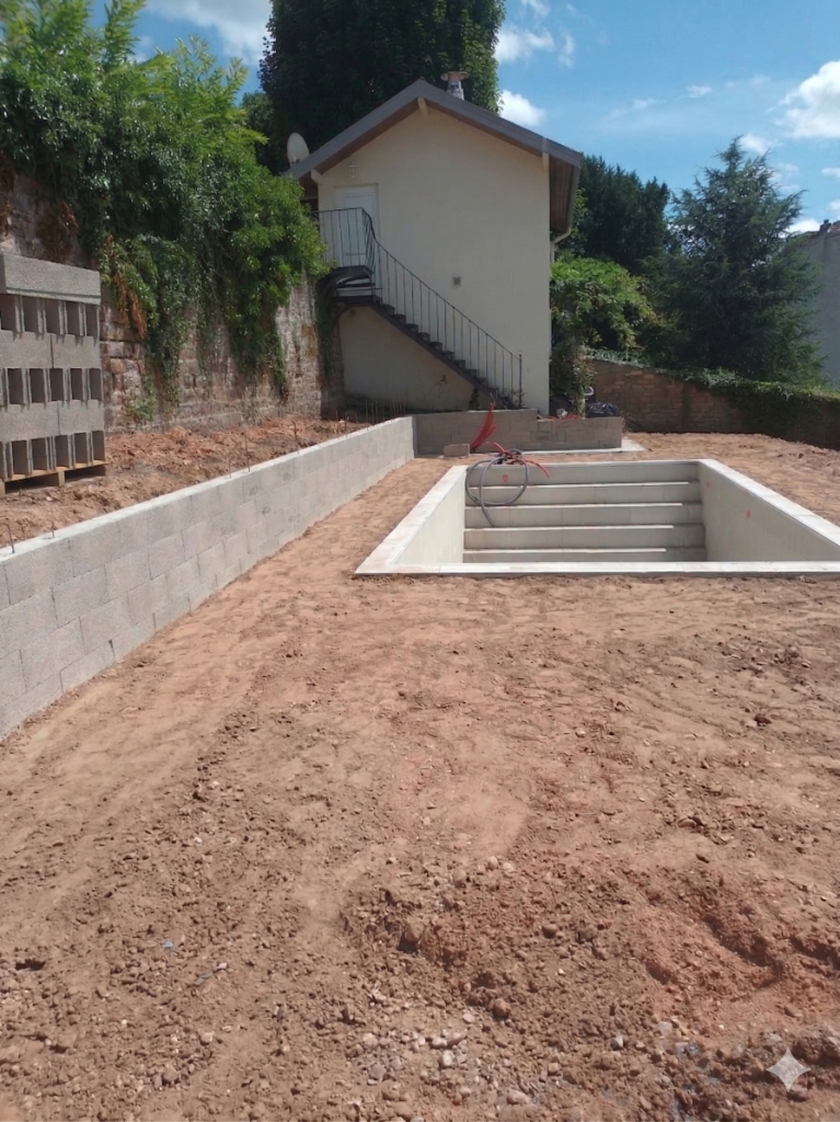 Chantier de construction de piscine en béton avec préparation des abords dans les Vosges